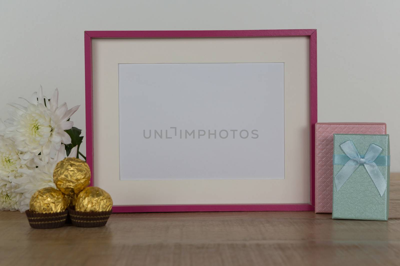 Chocolates, flowers, empty photo frame and gift boxes on wooden table