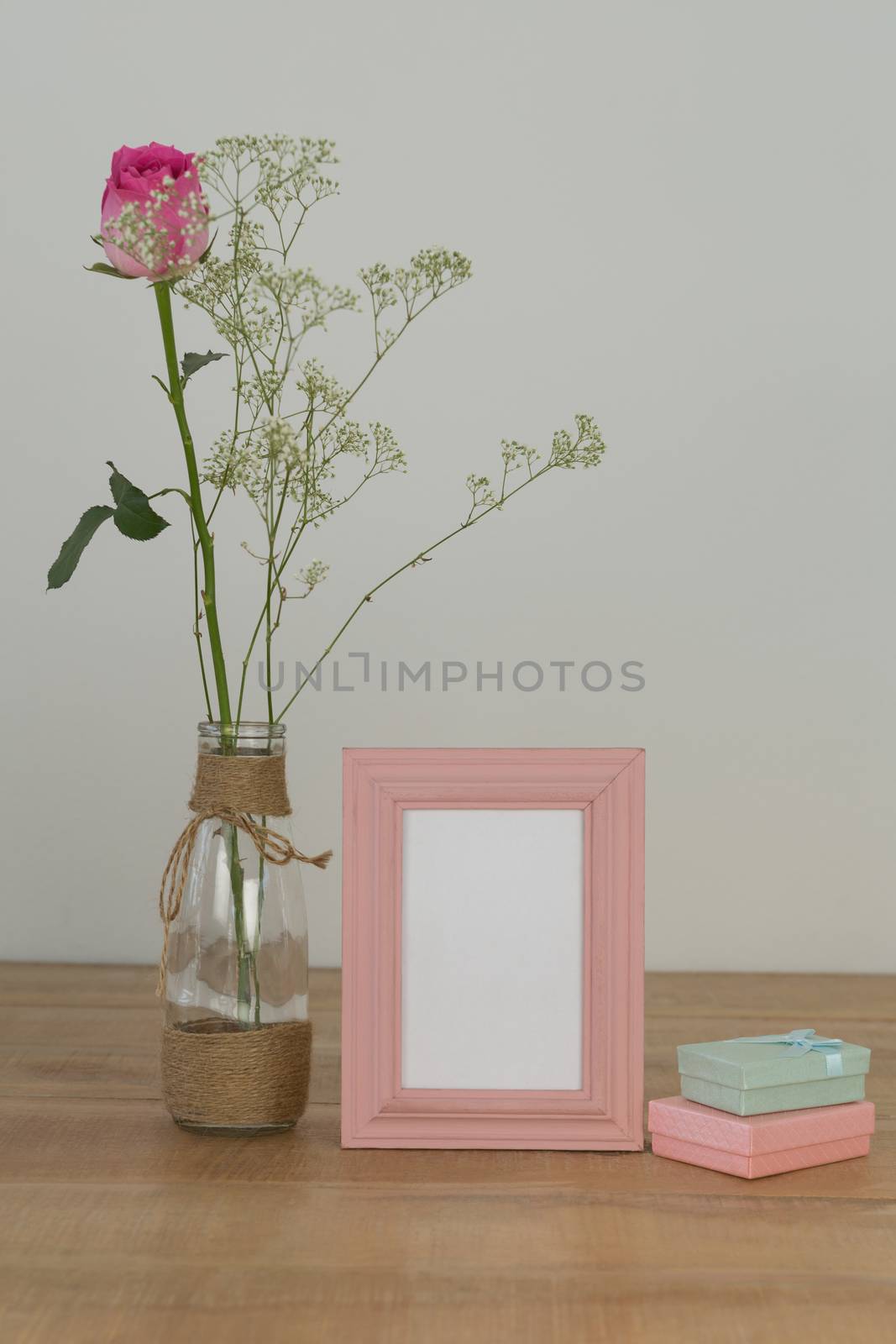 Rose flower, empty photo frame and gift boxes on wooden table