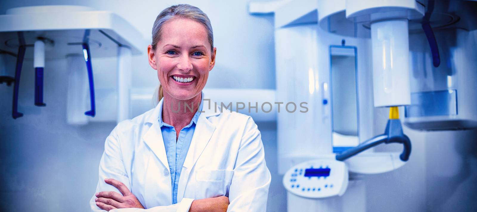 Portrait of female dentist smiling with arms crossed in dental clinic