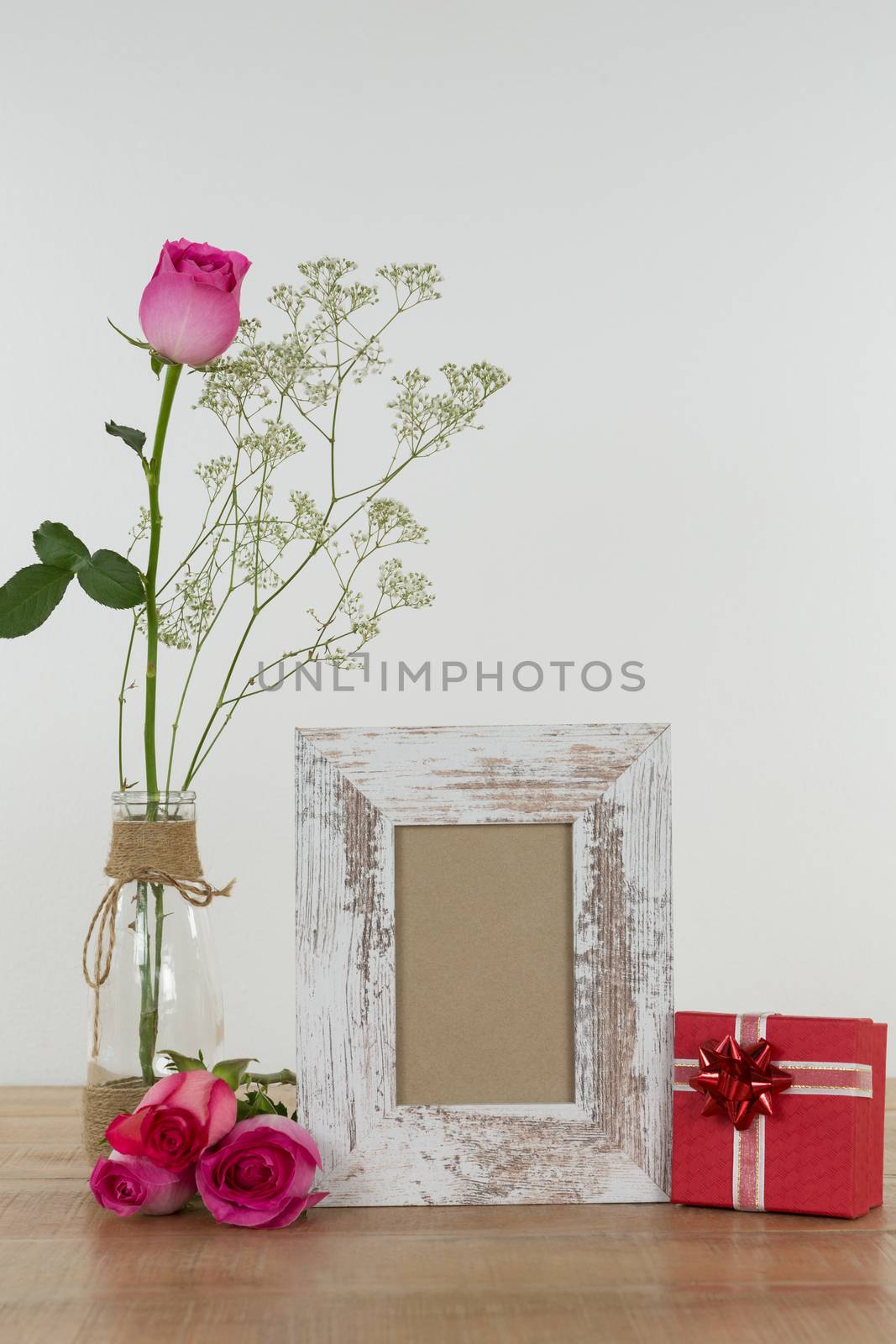 Rose flower, empty photo frame and gift boxes on wooden table