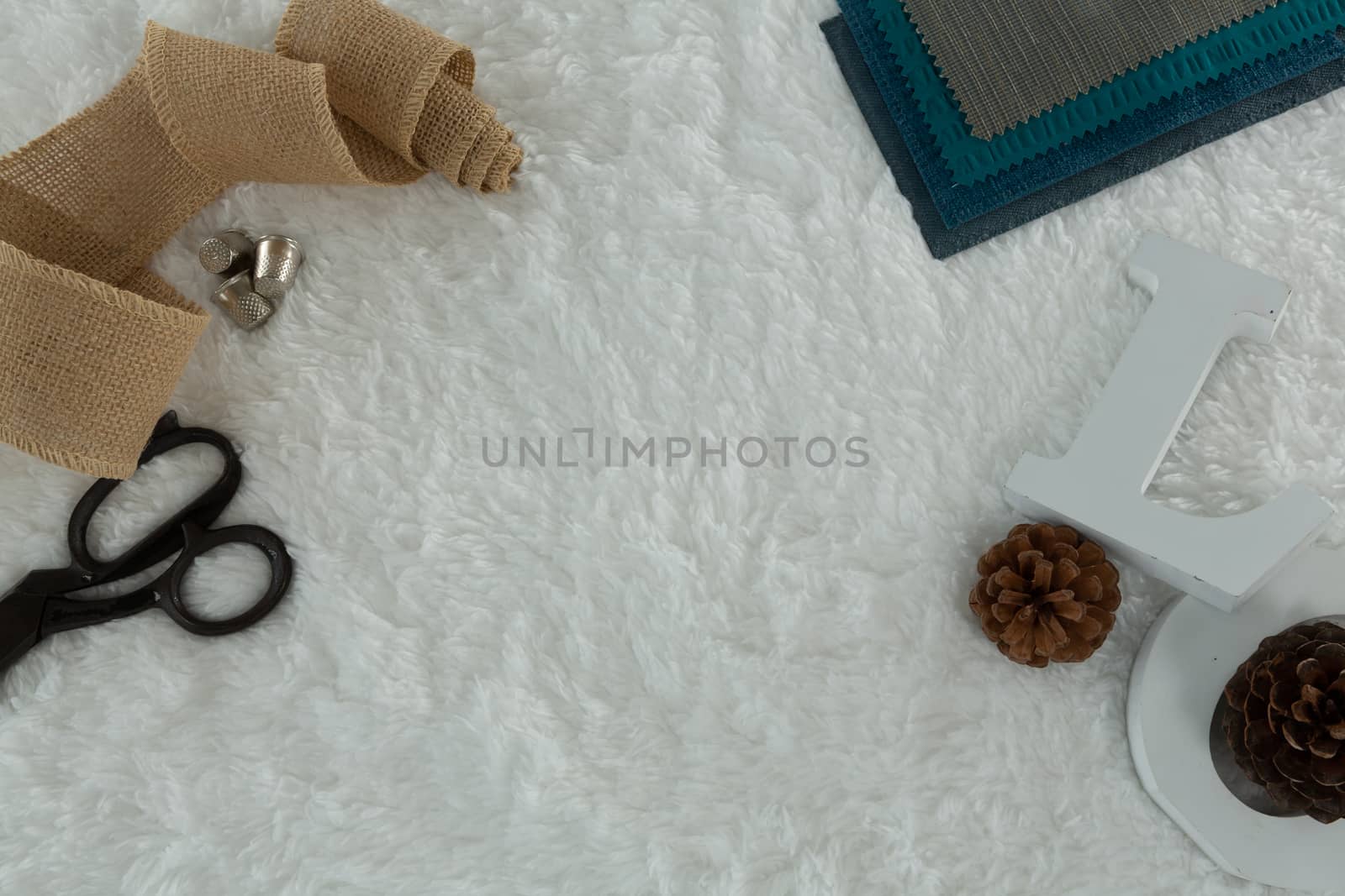 Overhead of textile and pine cone on white background
