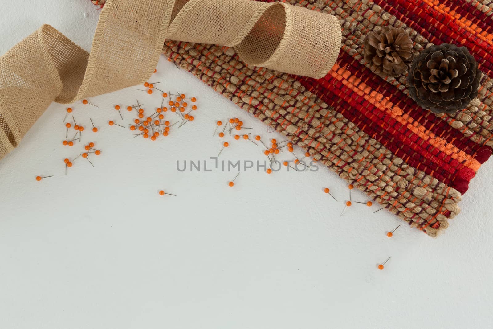 Overhead of textile and pine cone on white background