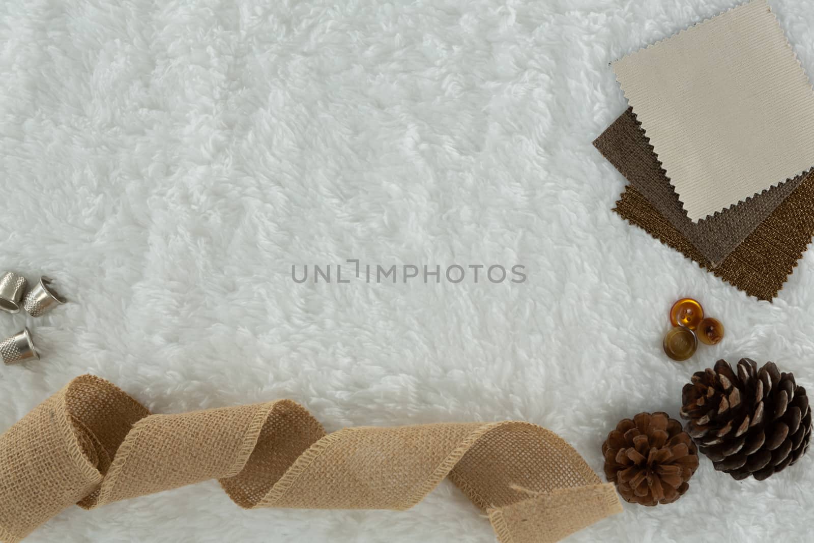 Overhead of textile and pine cone on white background