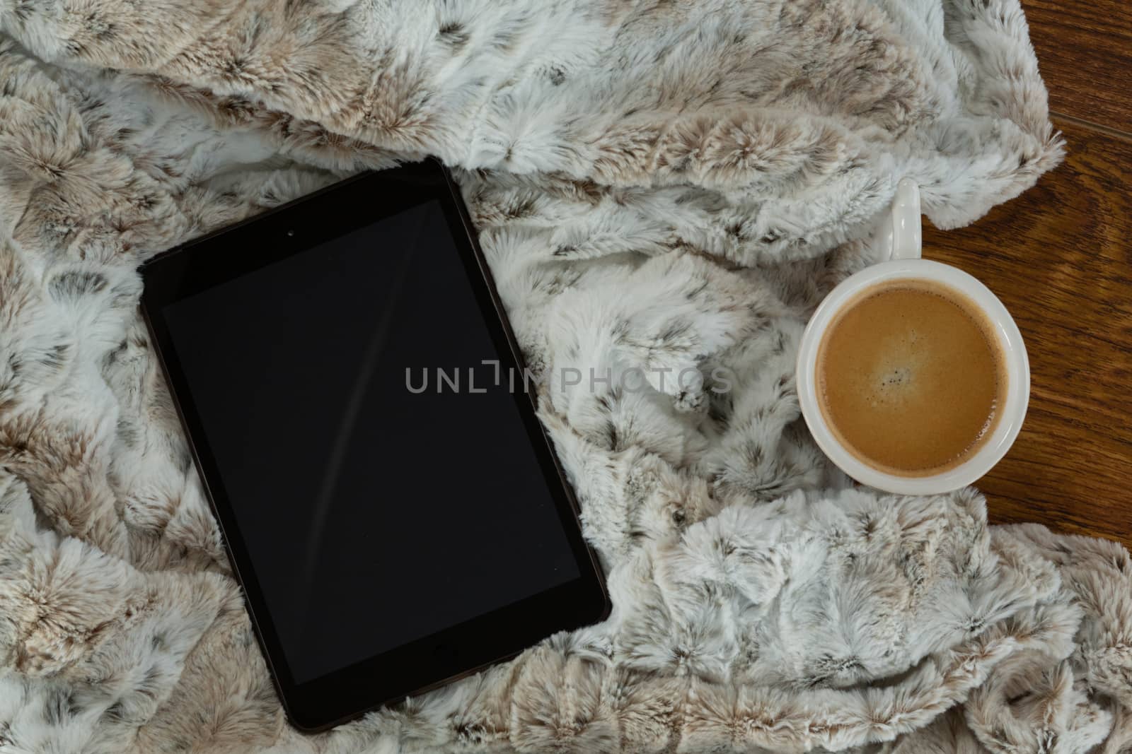 Close-up of digital tablet with blanket and coffee on wooden background