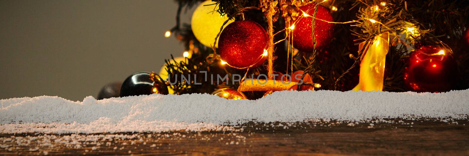 Wooden table with snow against christmas garlands on a pine