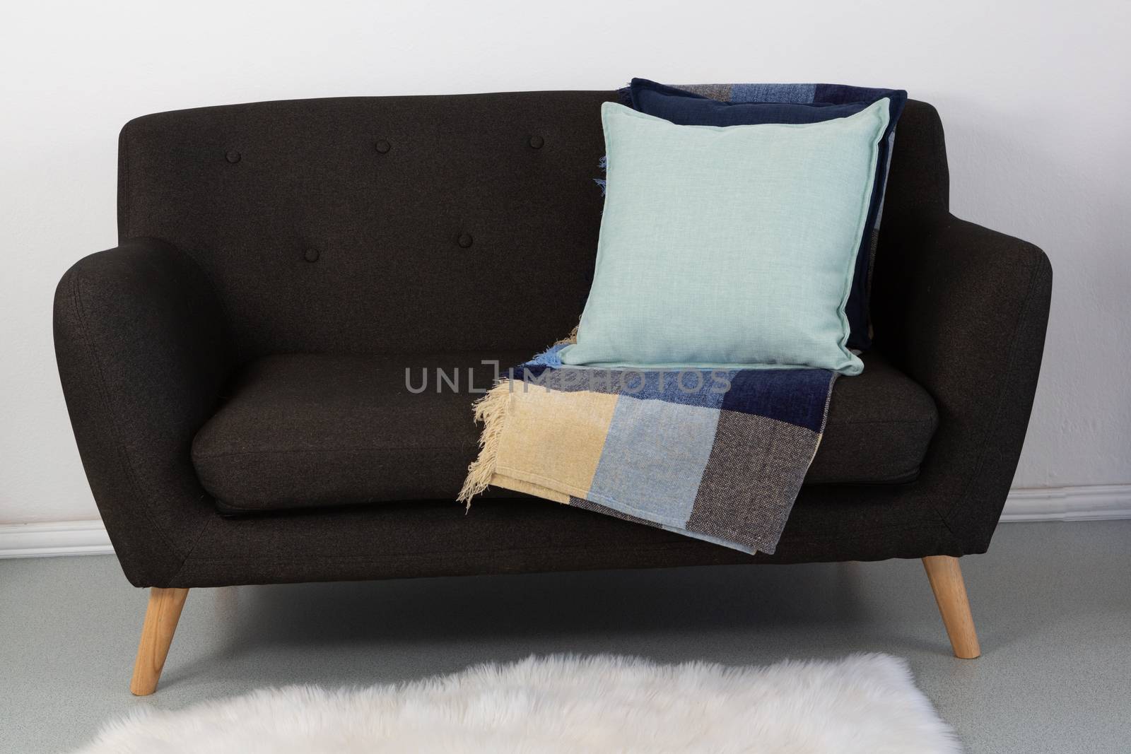 Close-up of cushions and blanket arranged on sofa