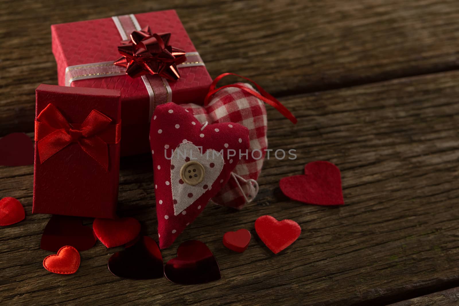 Heart shape decorations and gifts arranged on wooden plank
