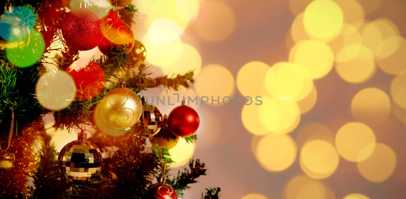 Defocused of Christmas tree lights and fireplace against red and gold christmas balls hanging in tree