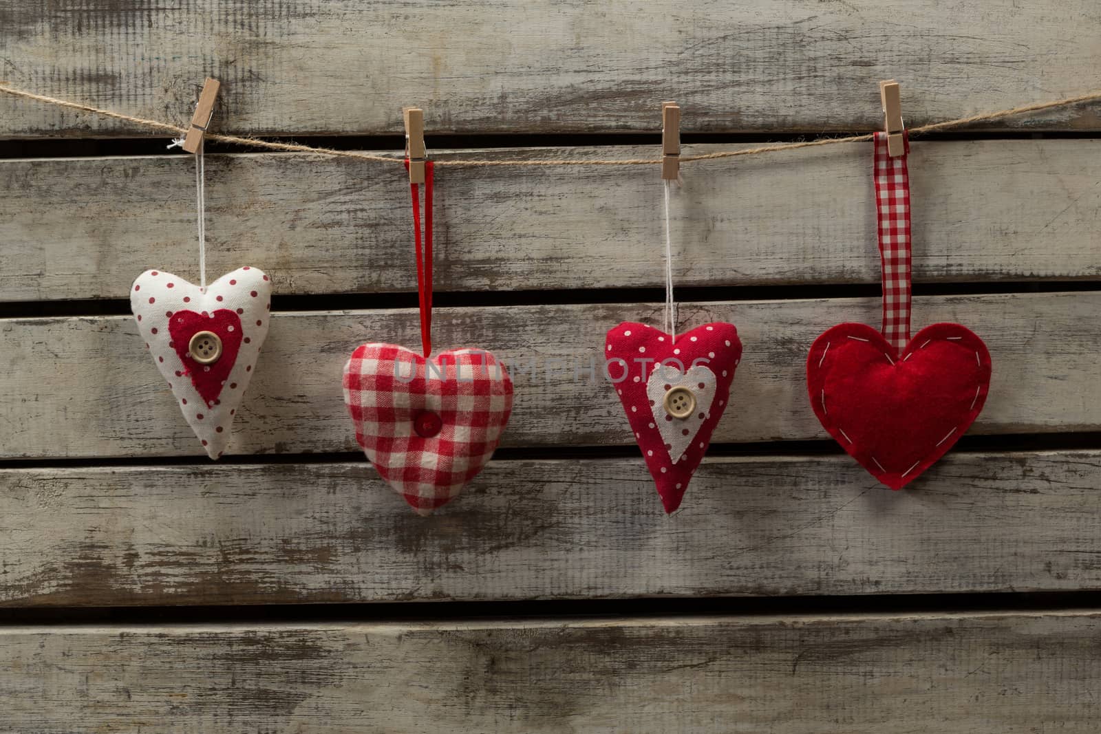 Heart shape decorations hanging on thread against wooden plank