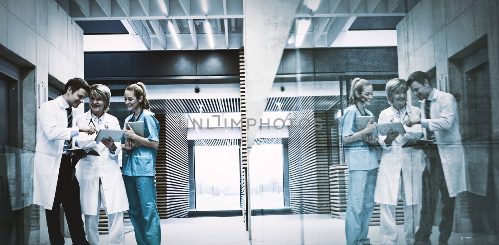 Medical team discussing over digital tablet in corridor at hospital