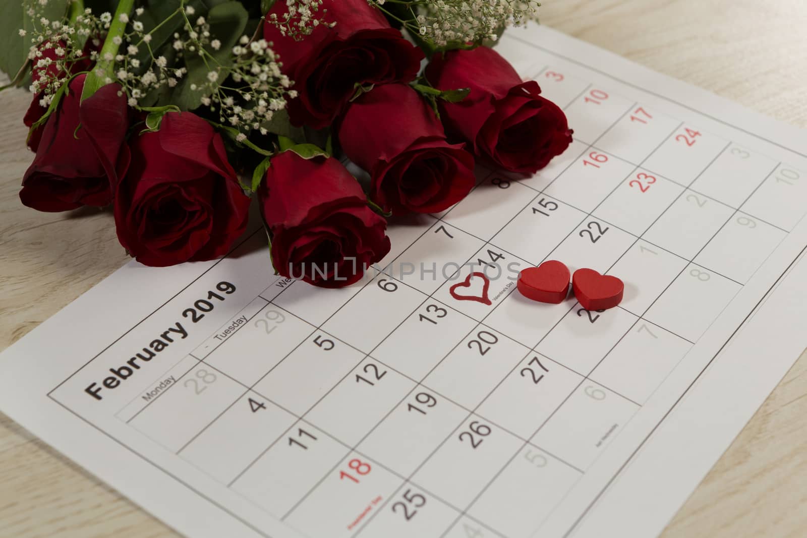 Close-up of rose bouquet with heart shape decorations on February calendar