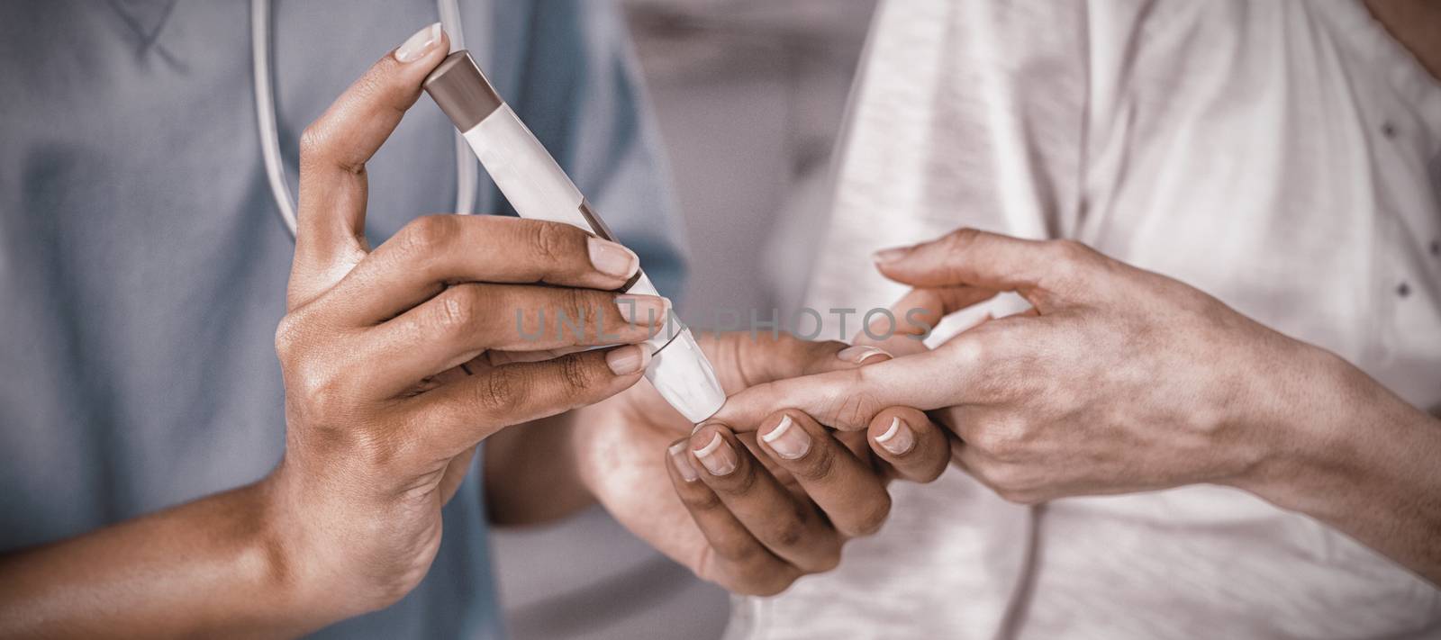 Mid section of doctor examining pregnant womans blood sugar in hospital