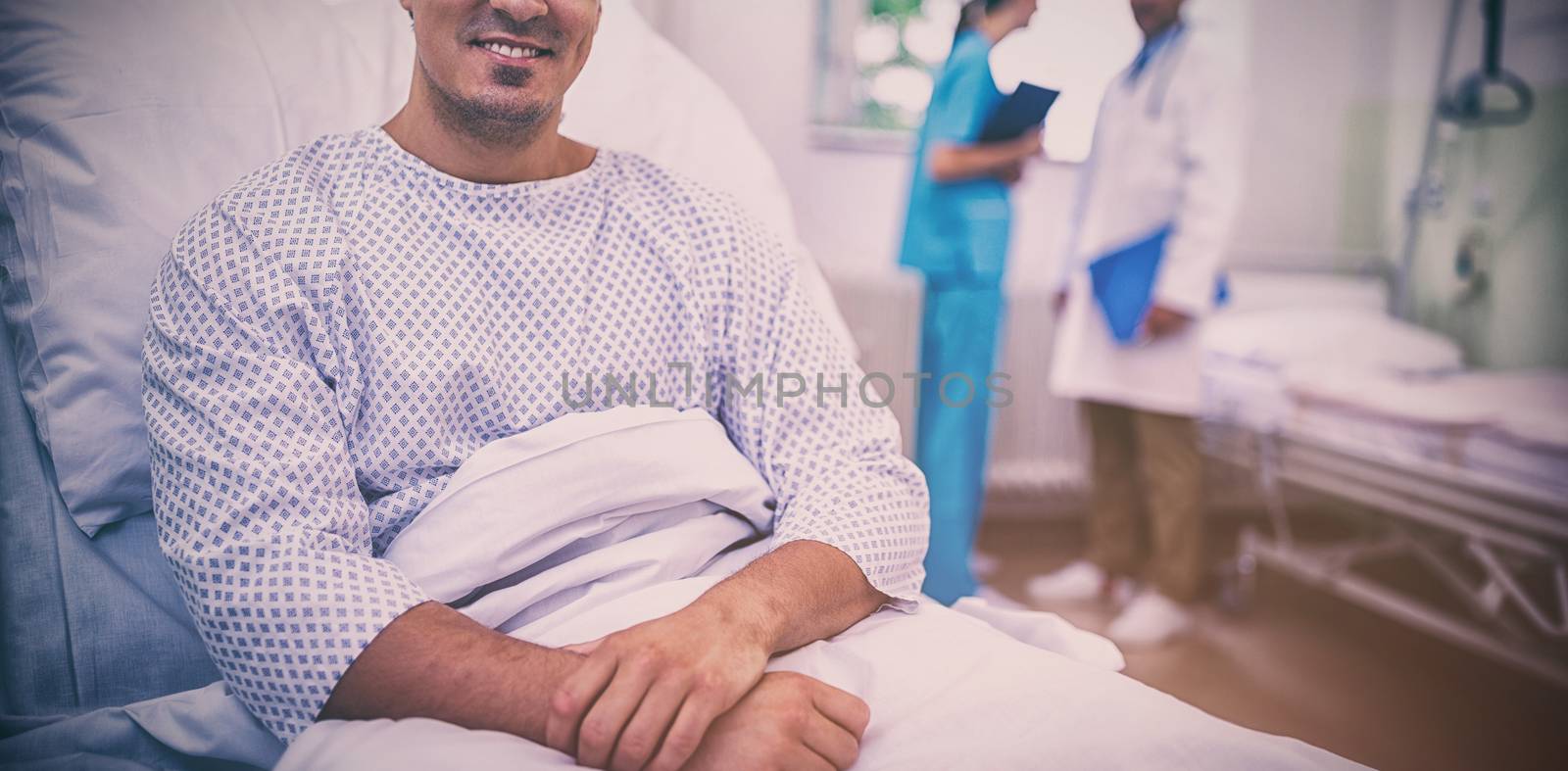 Portrait of smiling patient sitting on bed in hospital