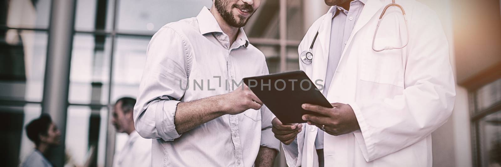 Doctor and patient having discussion on digital tablet of hospital