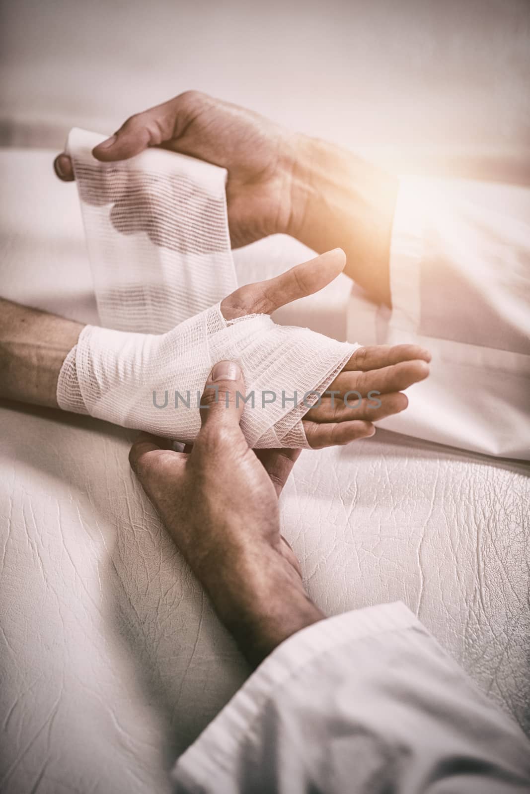 Physiotherapist putting bandage on injured hand of patient by Wavebreakmedia