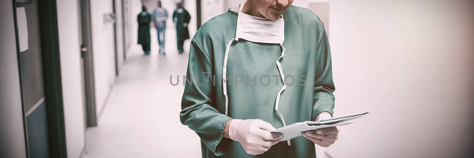 Surgeon checking report in corridor at hospital