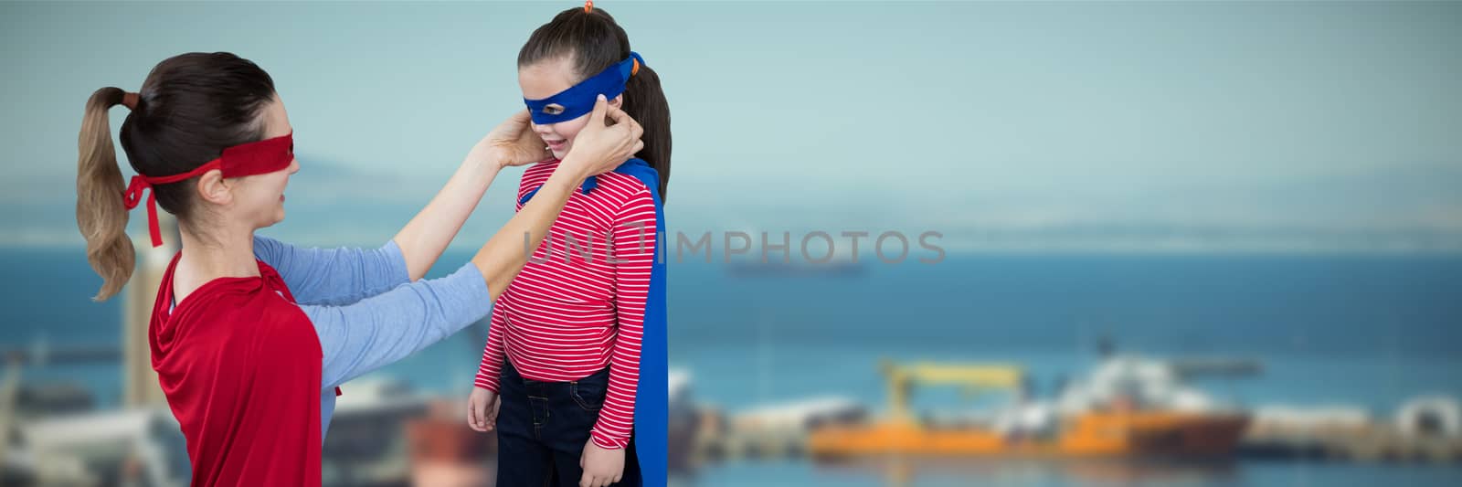 Mother and daughter pretending to be superhero against view of harbor