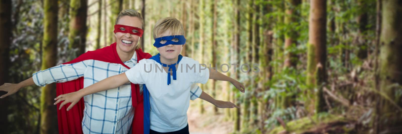 Mother and son pretending to be superhero against empty footpath amidst trees 