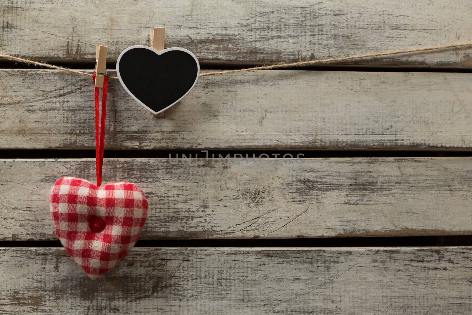 Heart shape decorations hanging on thread against wooden plank