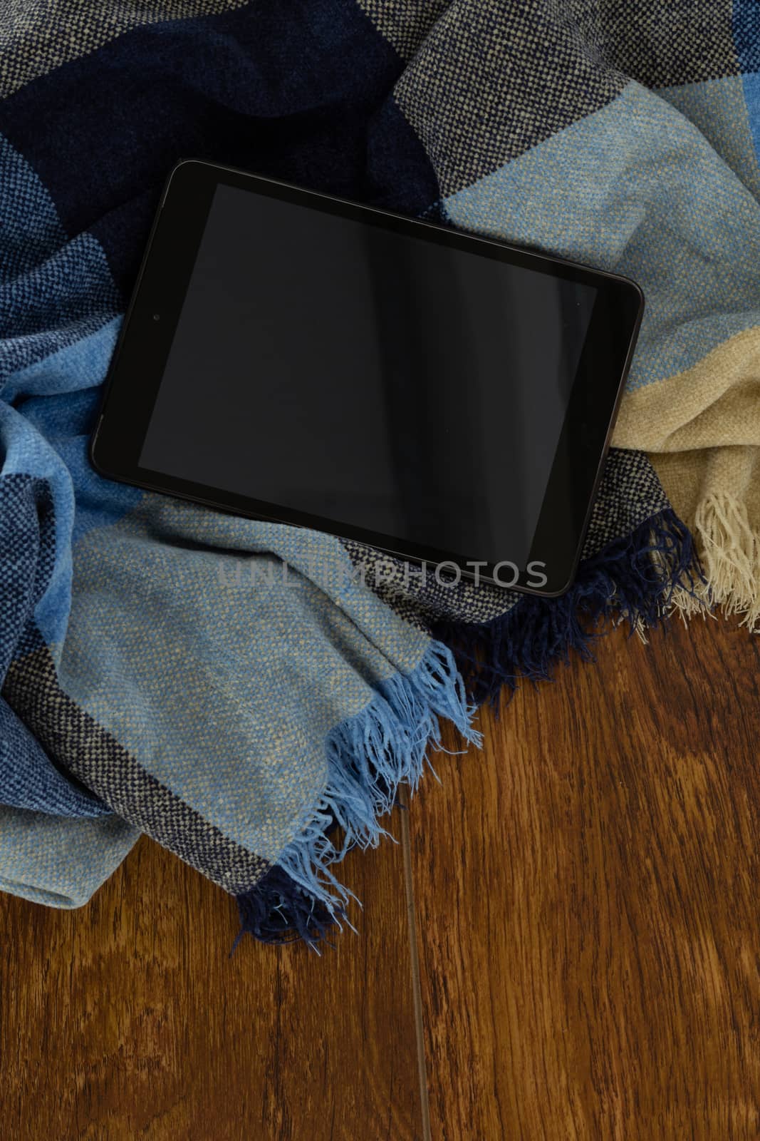 Close-up of digital tablet with blanket on wooden background
