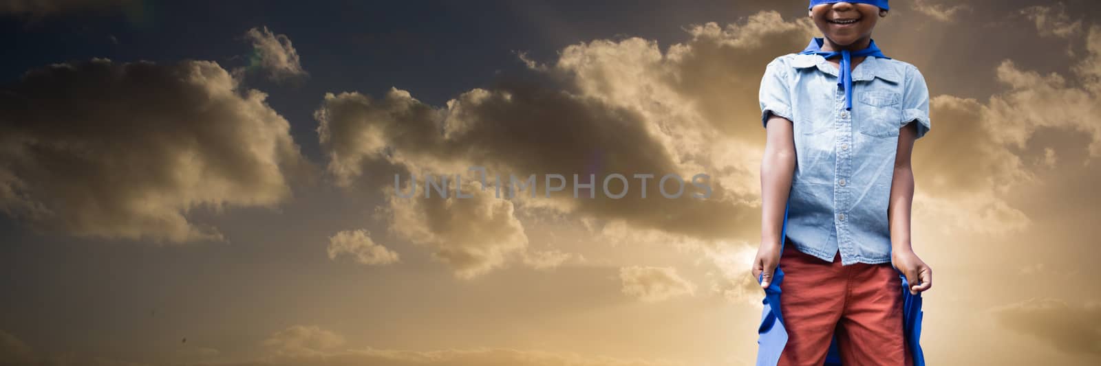 Boy pretending to be superhero against cloudy sky landscape