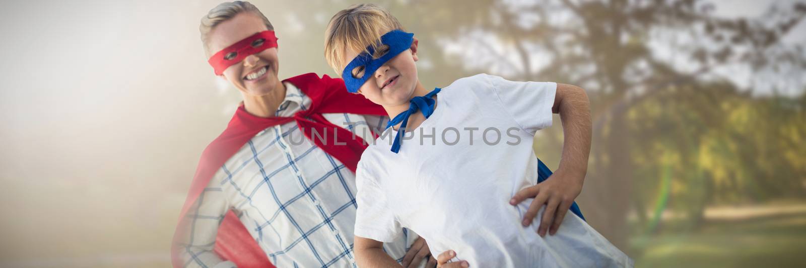 Mother and son pretending to be superhero against park on sunny day