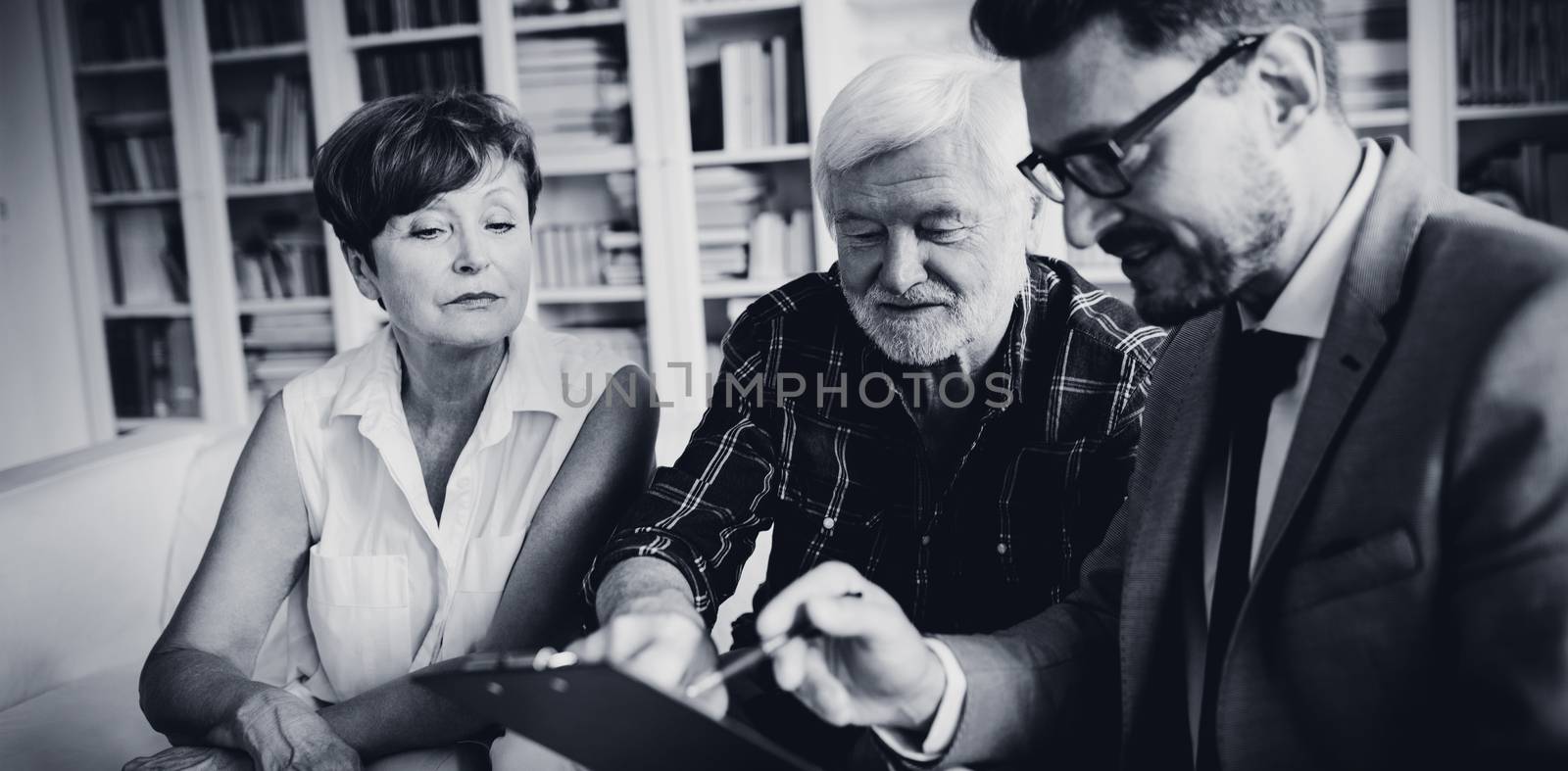 Senior couple planning their investments with financial advisor in living room