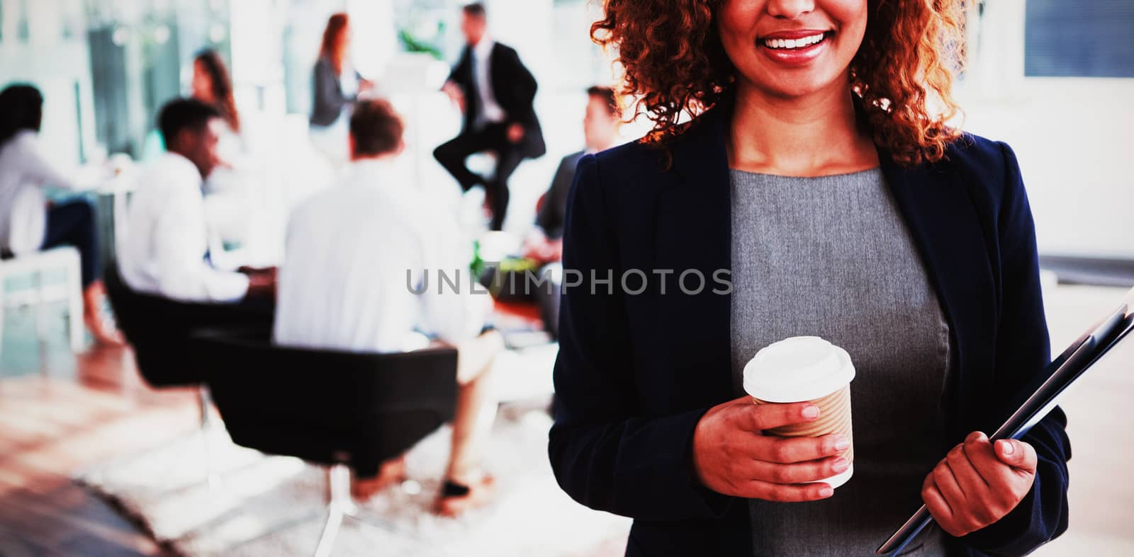 Portrait of smiling businesswoman holding disposable coffee cup in office