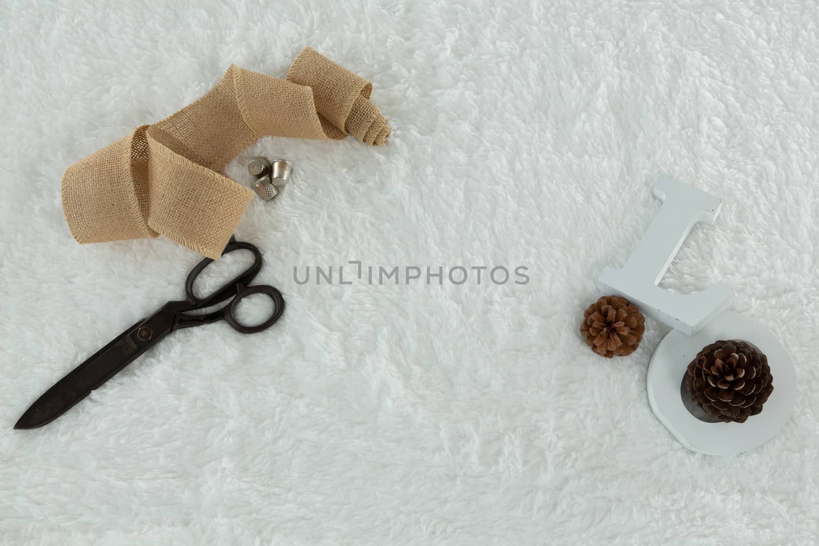 Overhead of textile, scissors and pine cone on white background
