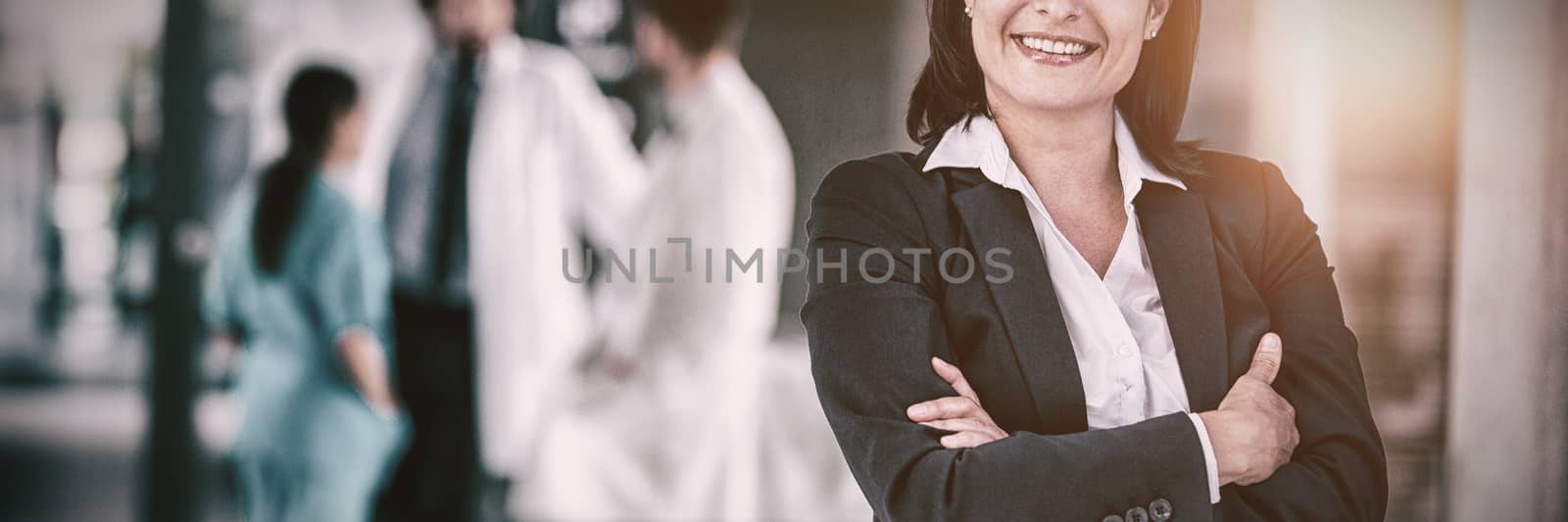 Portrait of businesswoman standing with hands folded at hospital