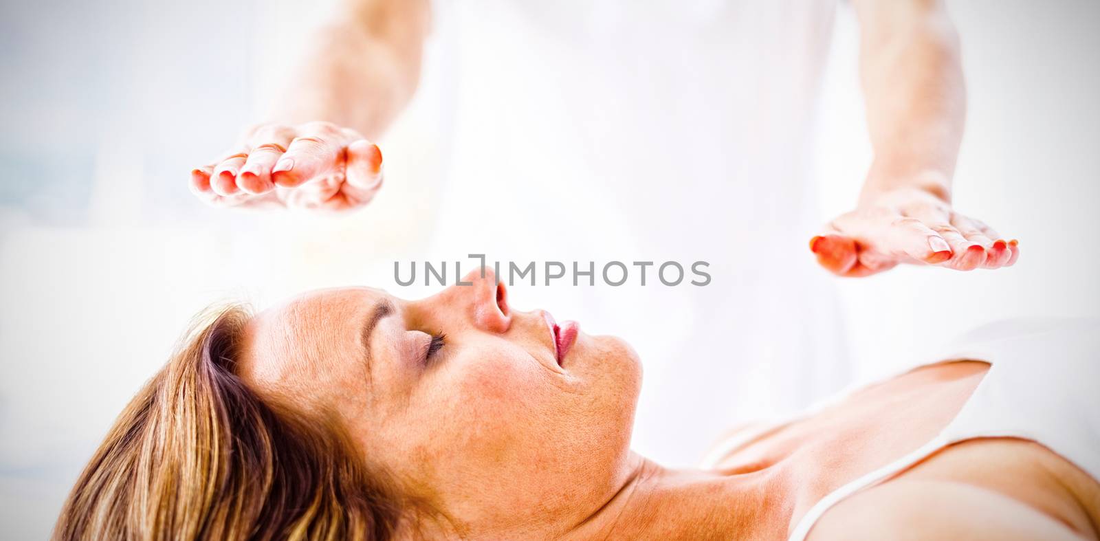 Midsection of therapist performing reiki treatment on woman at spa