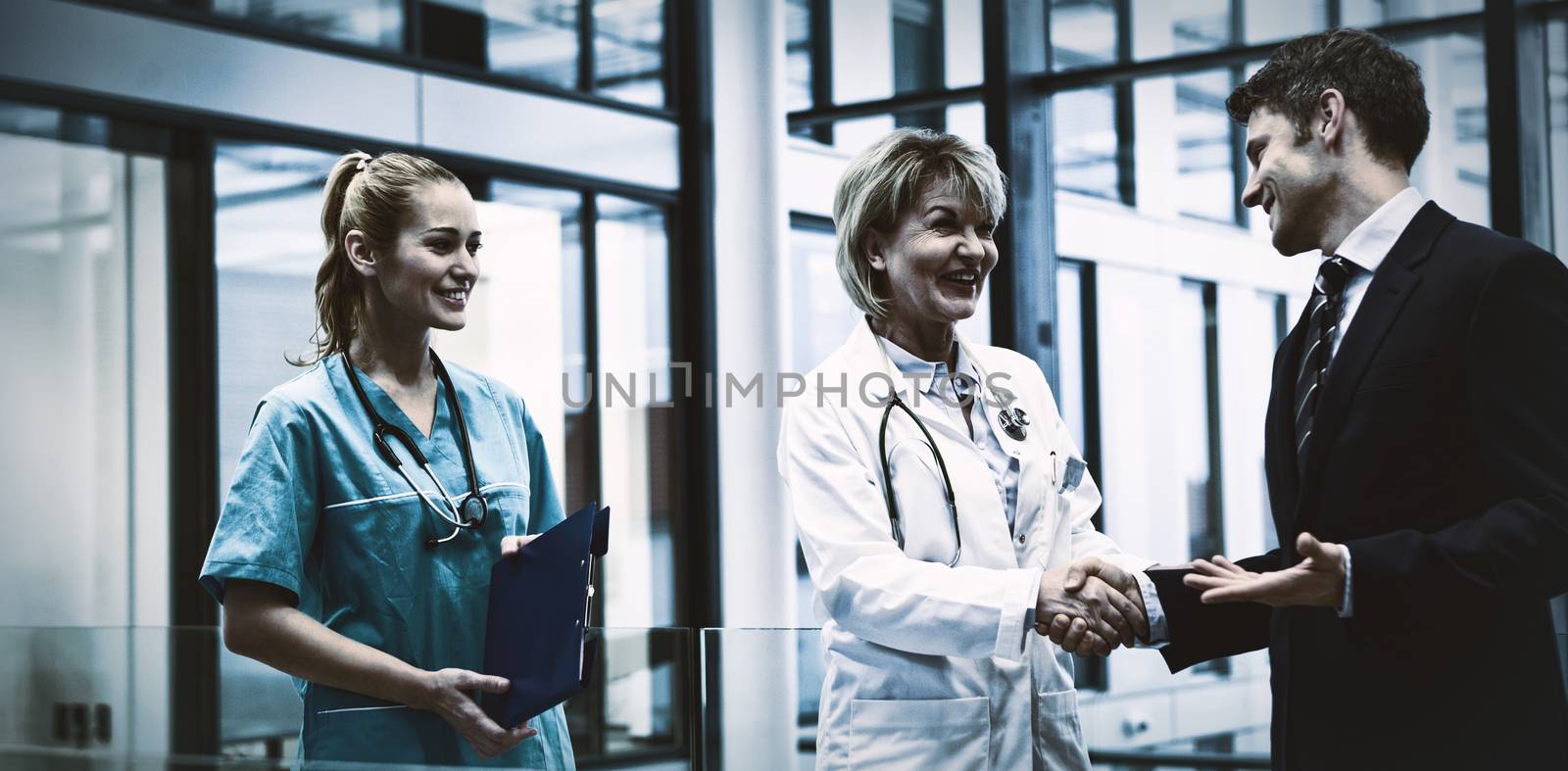 Female doctor shaking hands with businessman in hospital