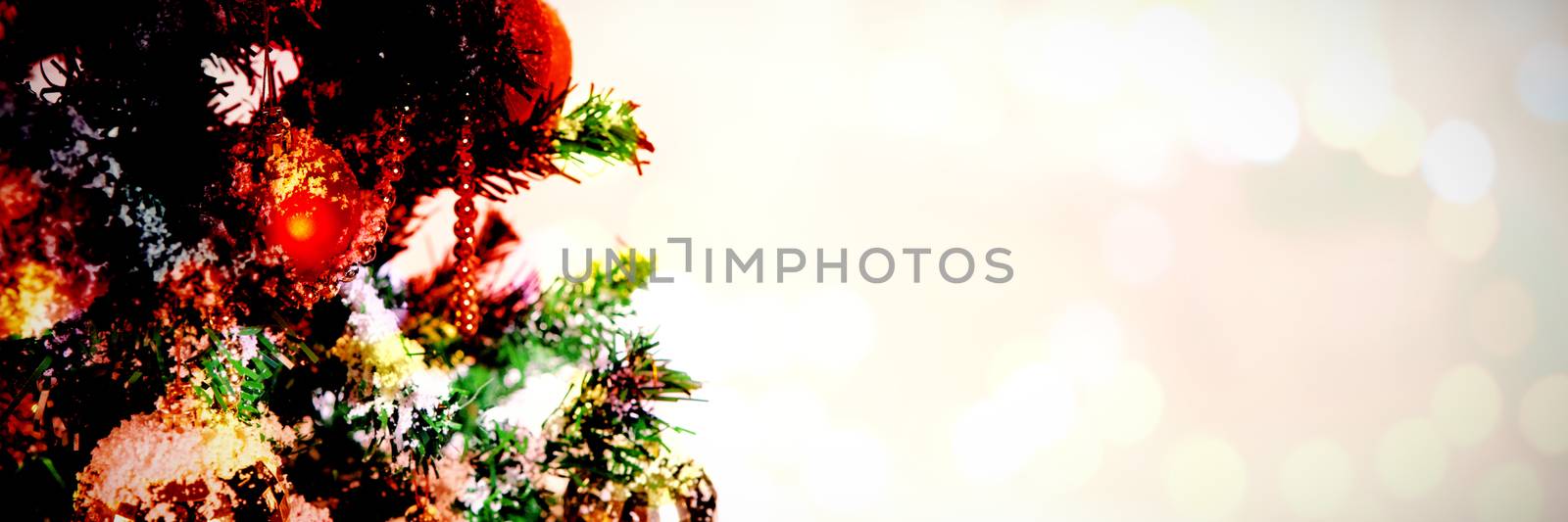 Composite image of table against christmas ornaments hanging in tree