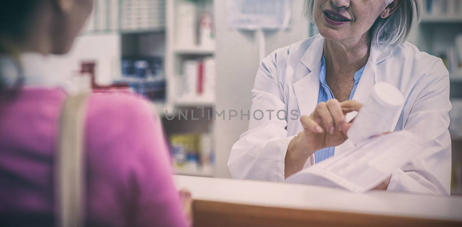 Pharmacist assisting the bottle of drug to customer in pharmacy