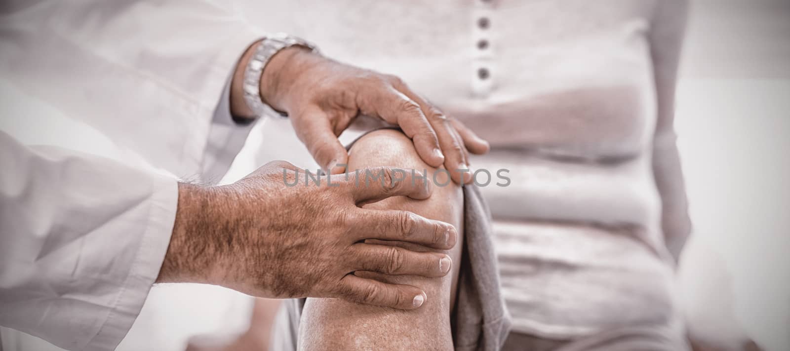 Physiotherapist giving knee therapy to senior woman in clinic