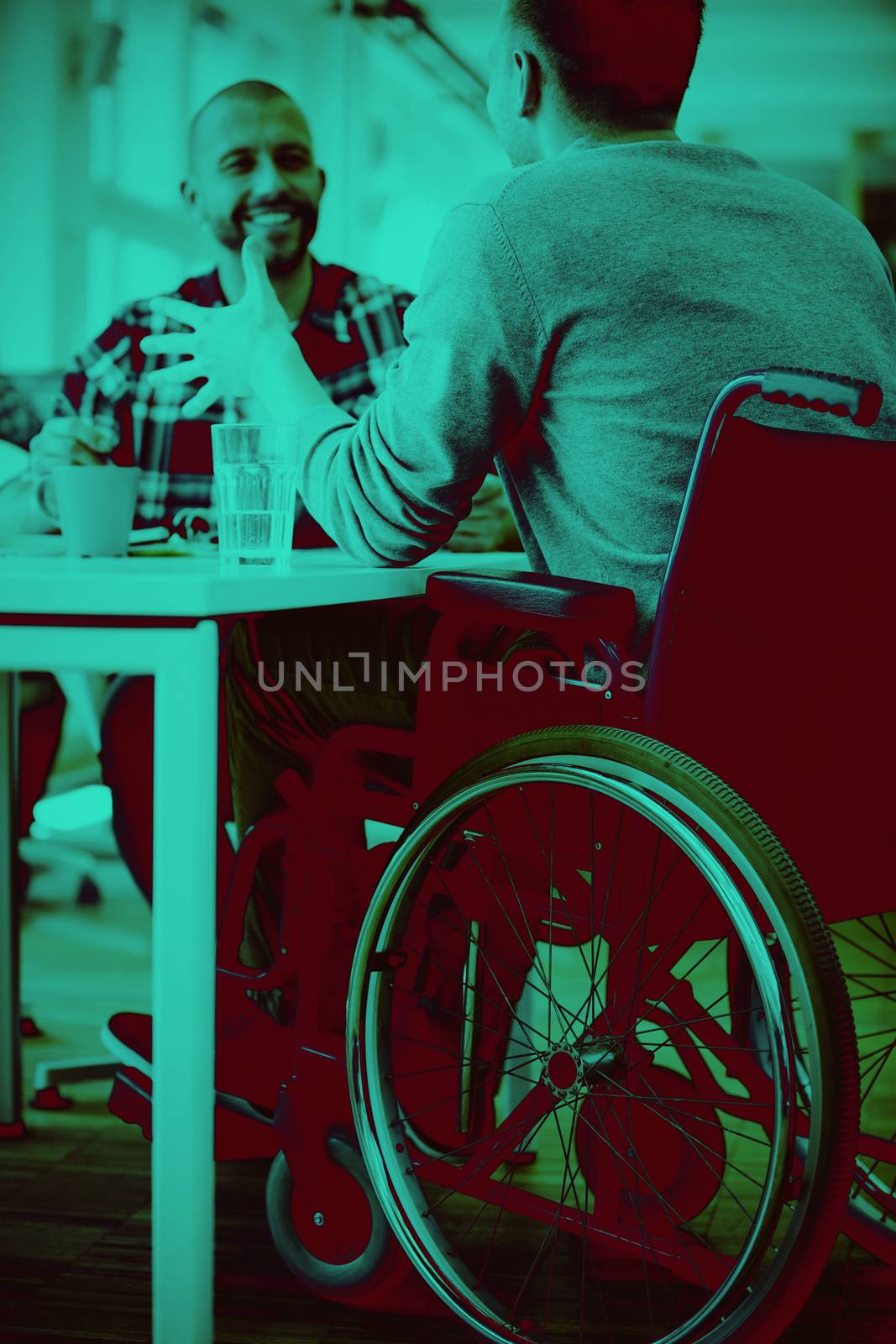 Happy handicap businessman discussing with colleague in creative office