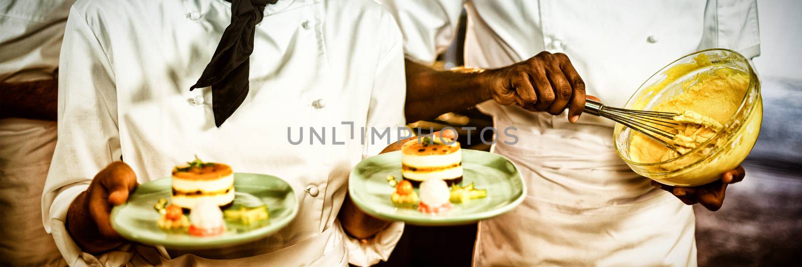 Female chef presenting dessert plates in commercial kitchen