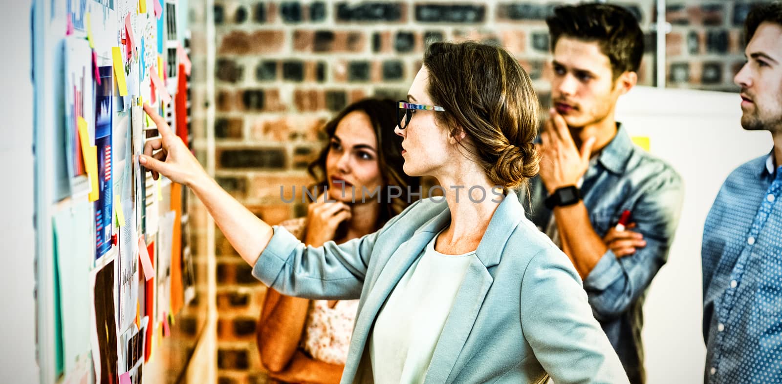 Business executives looking at sticky notes on whiteboard in office