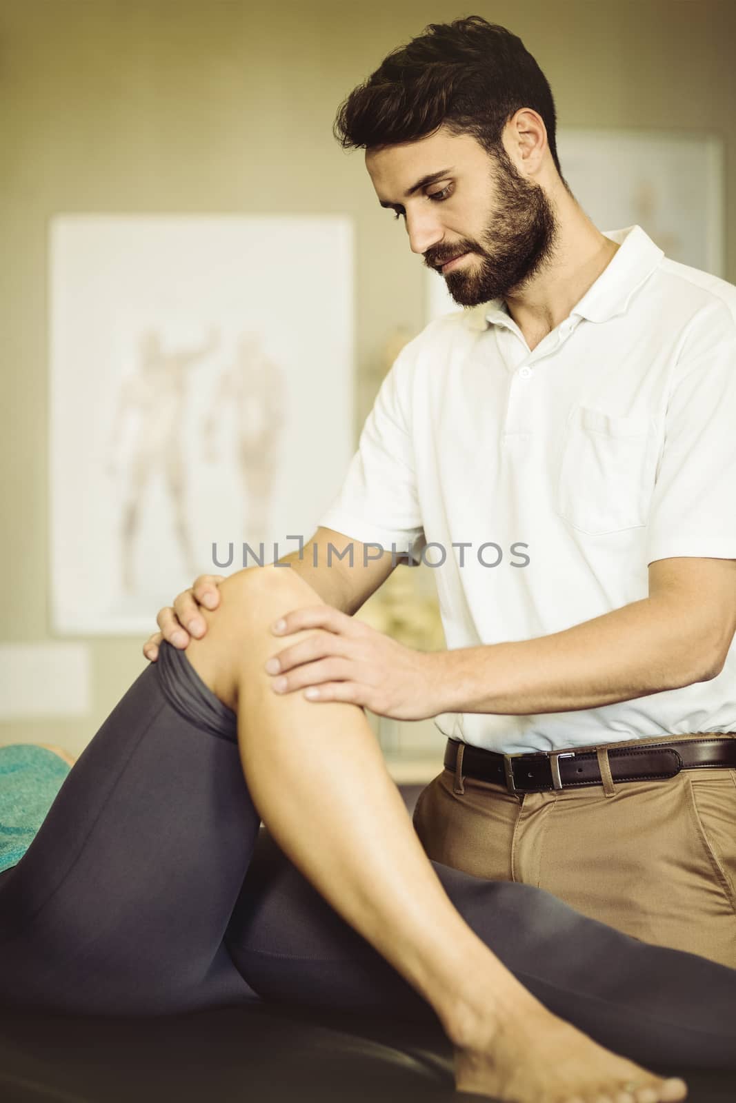 Male physiotherapist giving knee massage to female patient in clinic