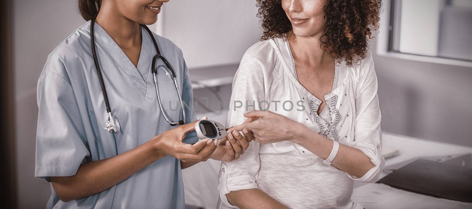 Doctor examining pregnant womans blood sugar in hospital