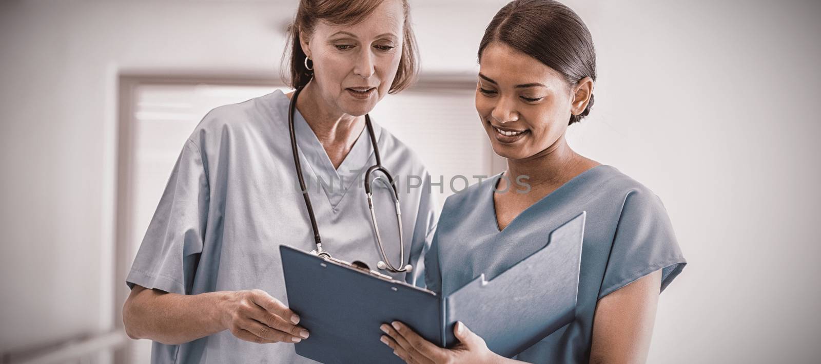 Nurse and doctor discussing over clipboard by Wavebreakmedia