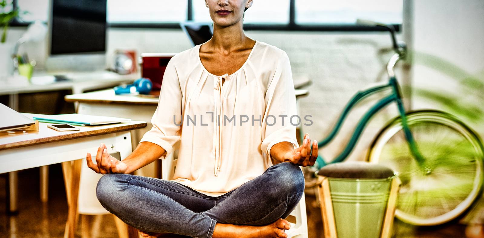 Woman sitting on chair and performing yoga by Wavebreakmedia