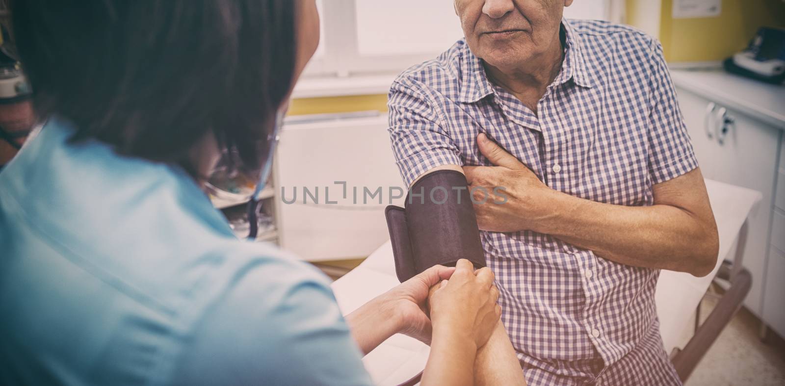 Female doctor checking blood pressure of patient by Wavebreakmedia