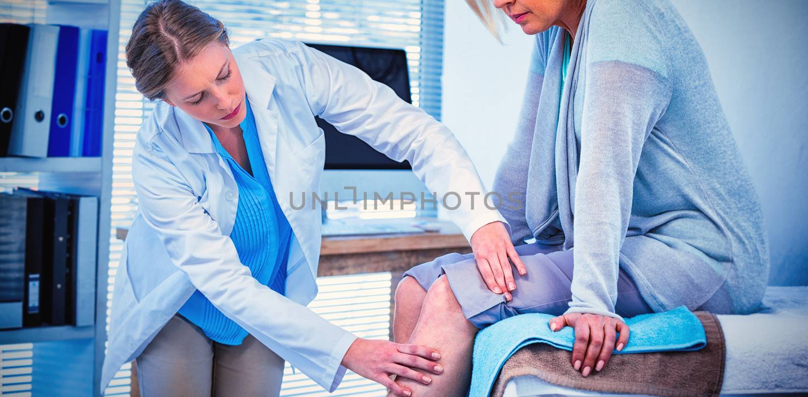 Doctor examining patient knee in clinic