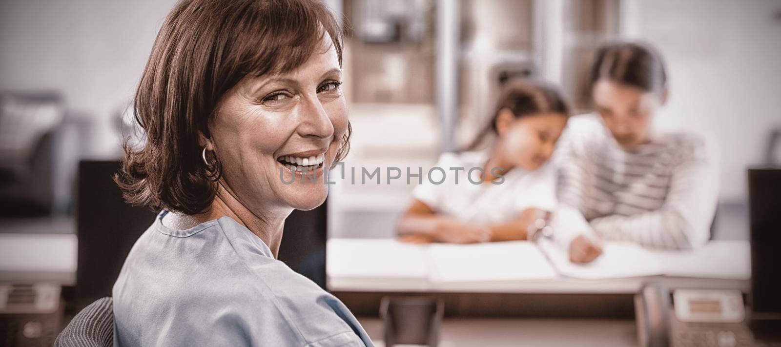 Portrait of smiling nurse sitting at desk in hospital
