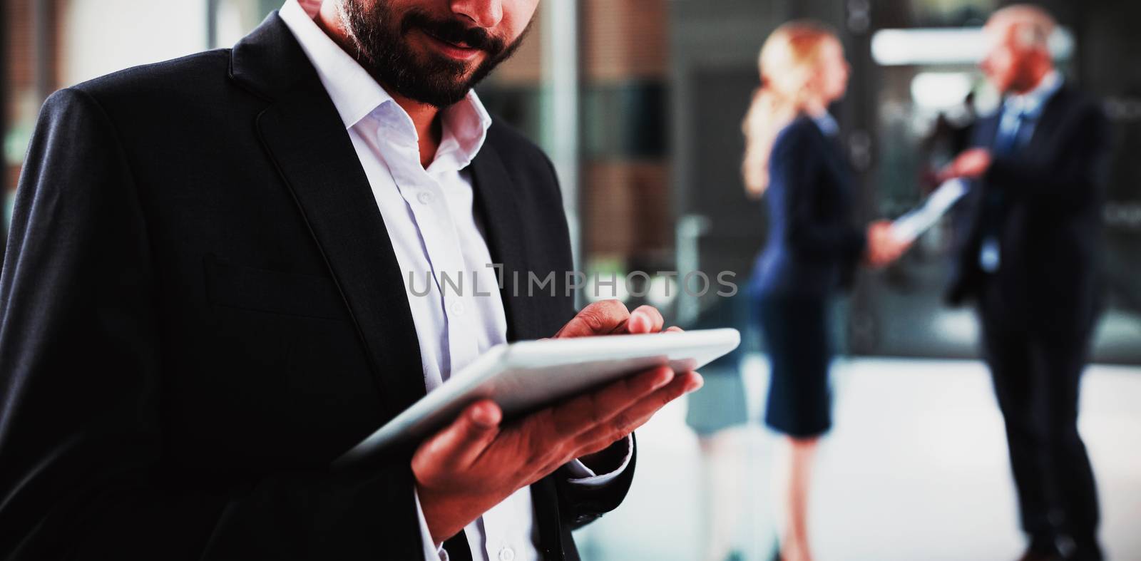 Smart businessman using digital tablet in office corridor