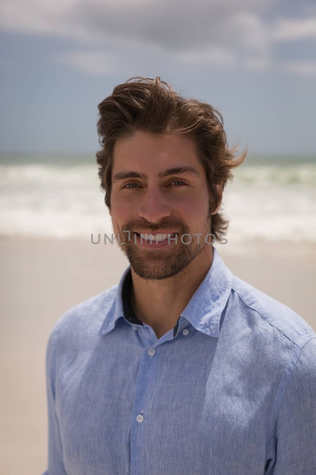 Portrait of happy man standing on the beach in front of the sea