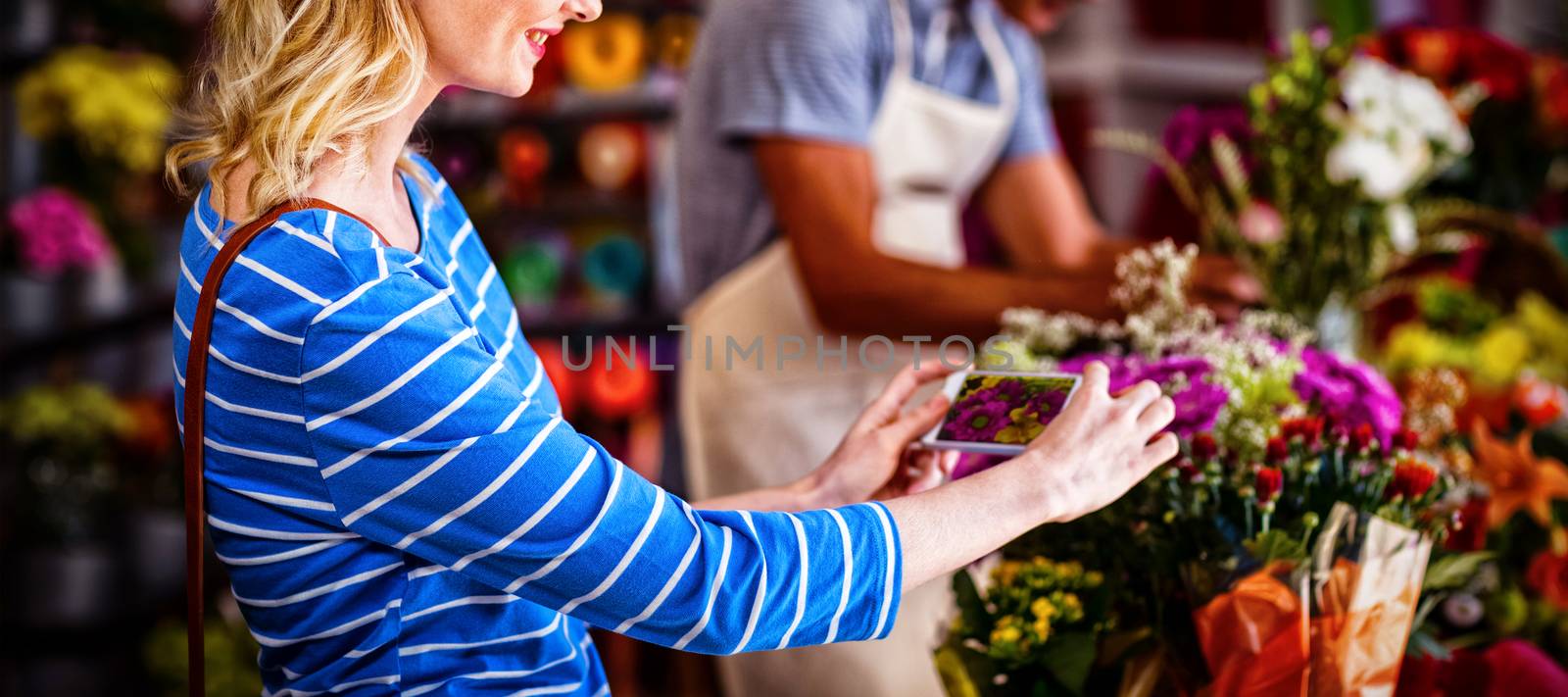 Woman taking photograph of flower bouquet in flower shop