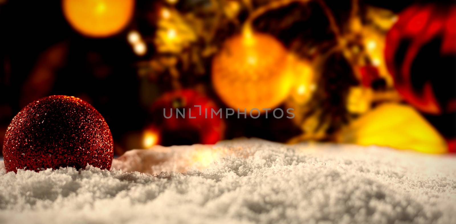 Christmas balls with an electric garland under the snow against christmas balls on a pine close-up