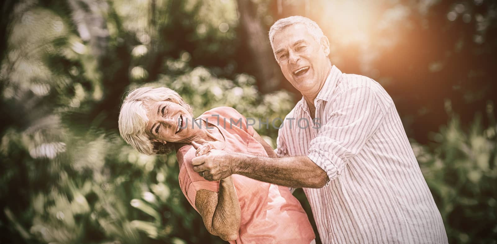 Portrait of senior couple enjoying while dancing in yard 